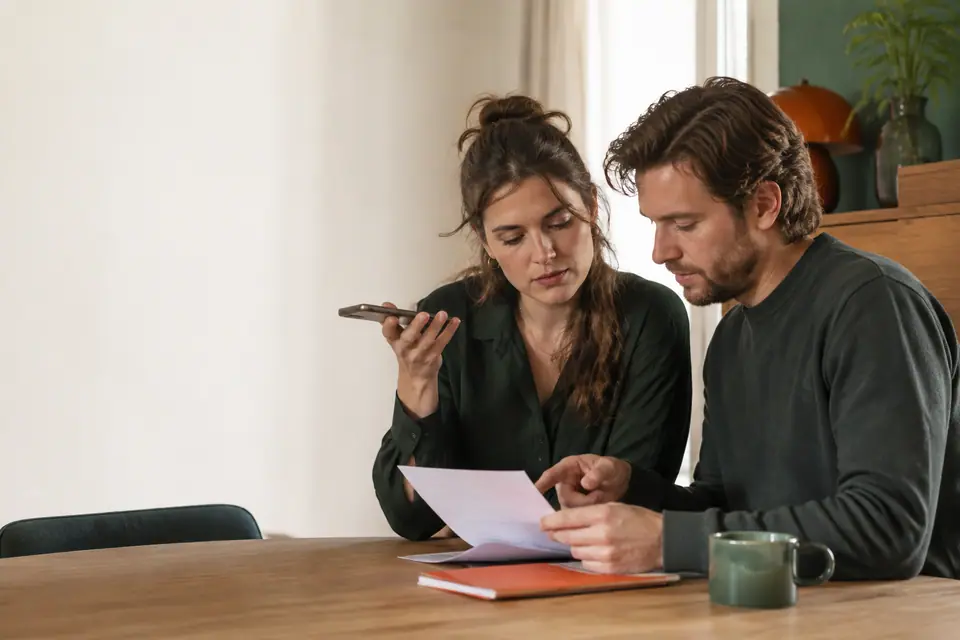 Consumenten bespreken thuis een document tijdens telefonisch contact