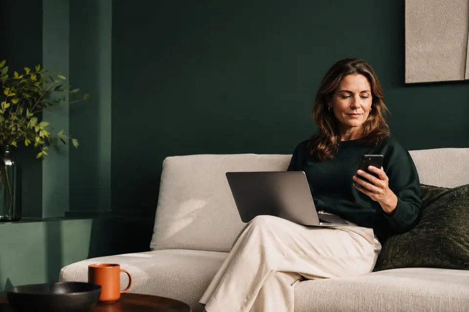 Vrouw gebruikt thuis rustig haar laptop en telefoon